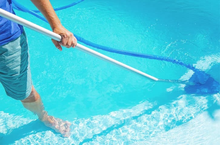 Photo of pool cleaner standing in blue swimming pool