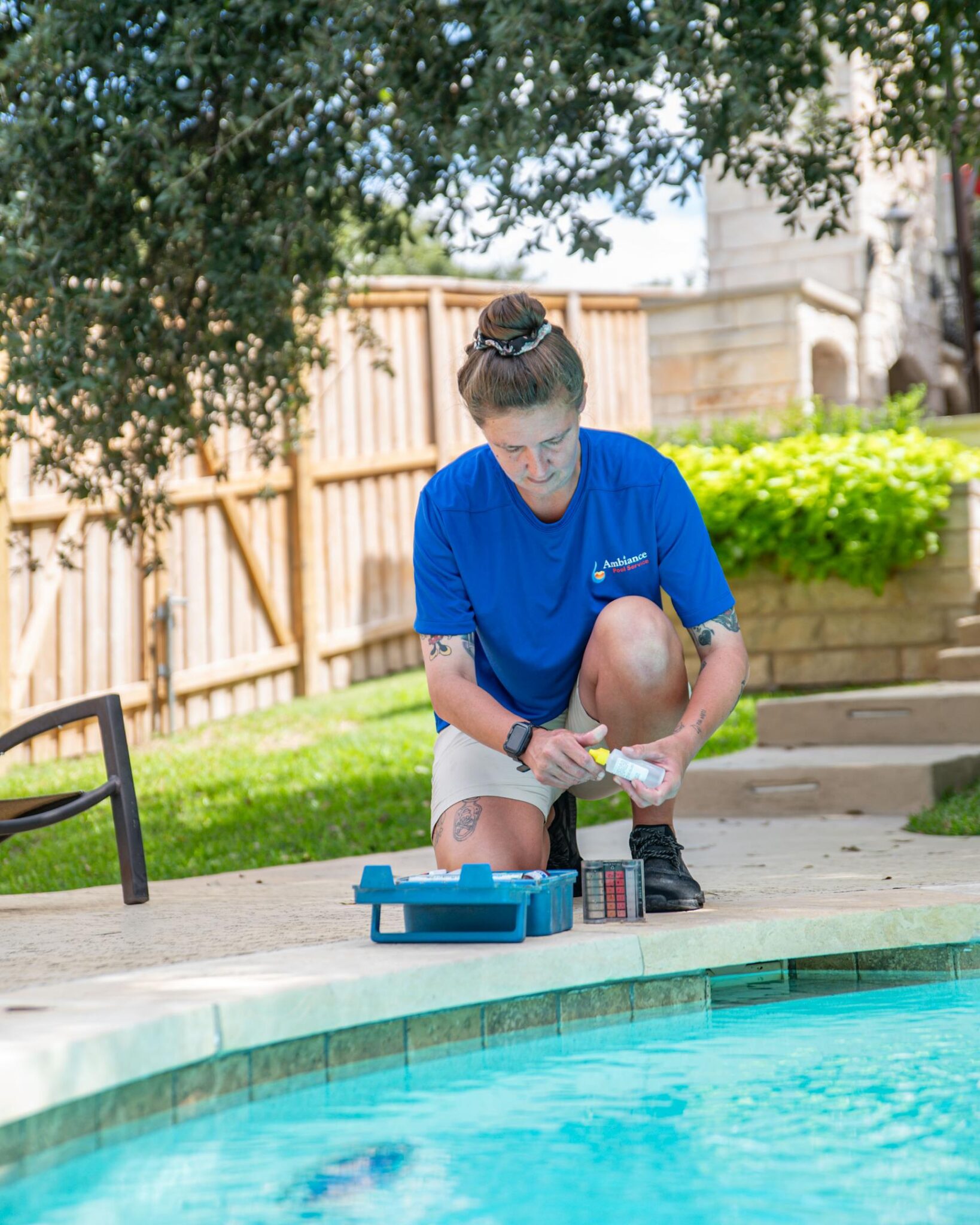 Ambiance Pool tech checking water chemistry near clear pool.